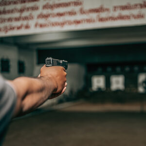 Professionals practice shooting a 9mm pistol inside a shooting range.
