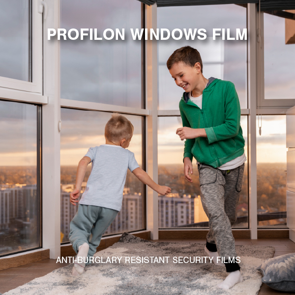 Two children playing safely near large glass windows protected by Profilon Windows FIM security films in a high-rise apartment.