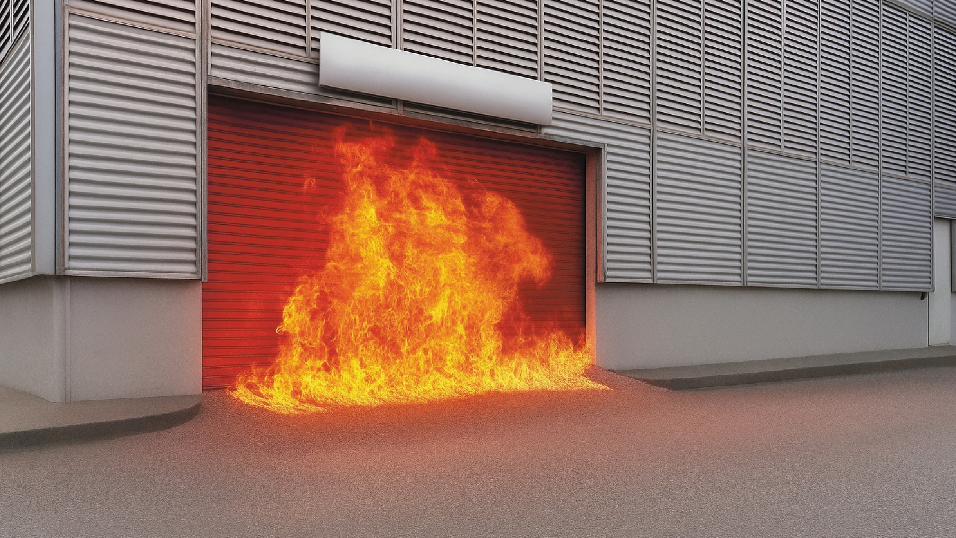Exterior fire-rated roller shutter under intense flame conditions at an industrial facility.